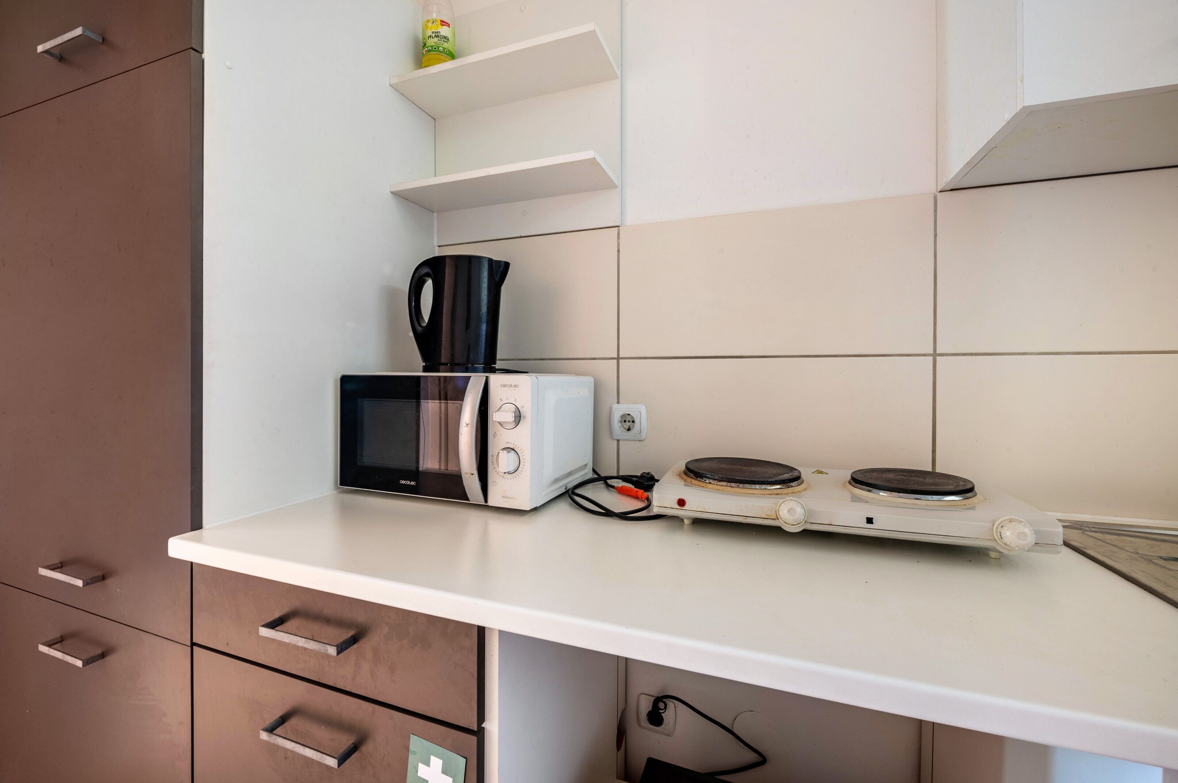 A kitchen with a microwave, toaster, and kettle on a white countertop.