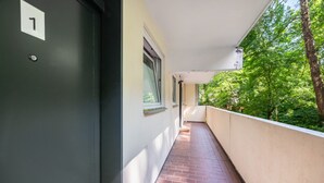 Un pasillo con un cartel con el número 1, una ventana y un balcón con vistas a la vegetación.