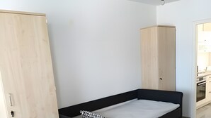 Une chambre avec un lit noir, une armoire en bois et une porte blanche.