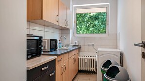 Cocina compacta con microondas, tostadora y pileta. Se ve una ventana con vista a follaje.