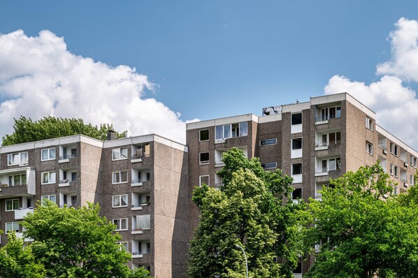 Un edificio residencial de varios pisos con balcones, ventanas y un cielo despejado.
