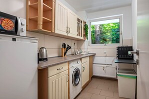 A compact kitchen with a washing machine, a kettle, and a microwave. - Apartment 'Mk  Delmenhorst 4' with Balcony and Wi-Fi (Delmenhorst)