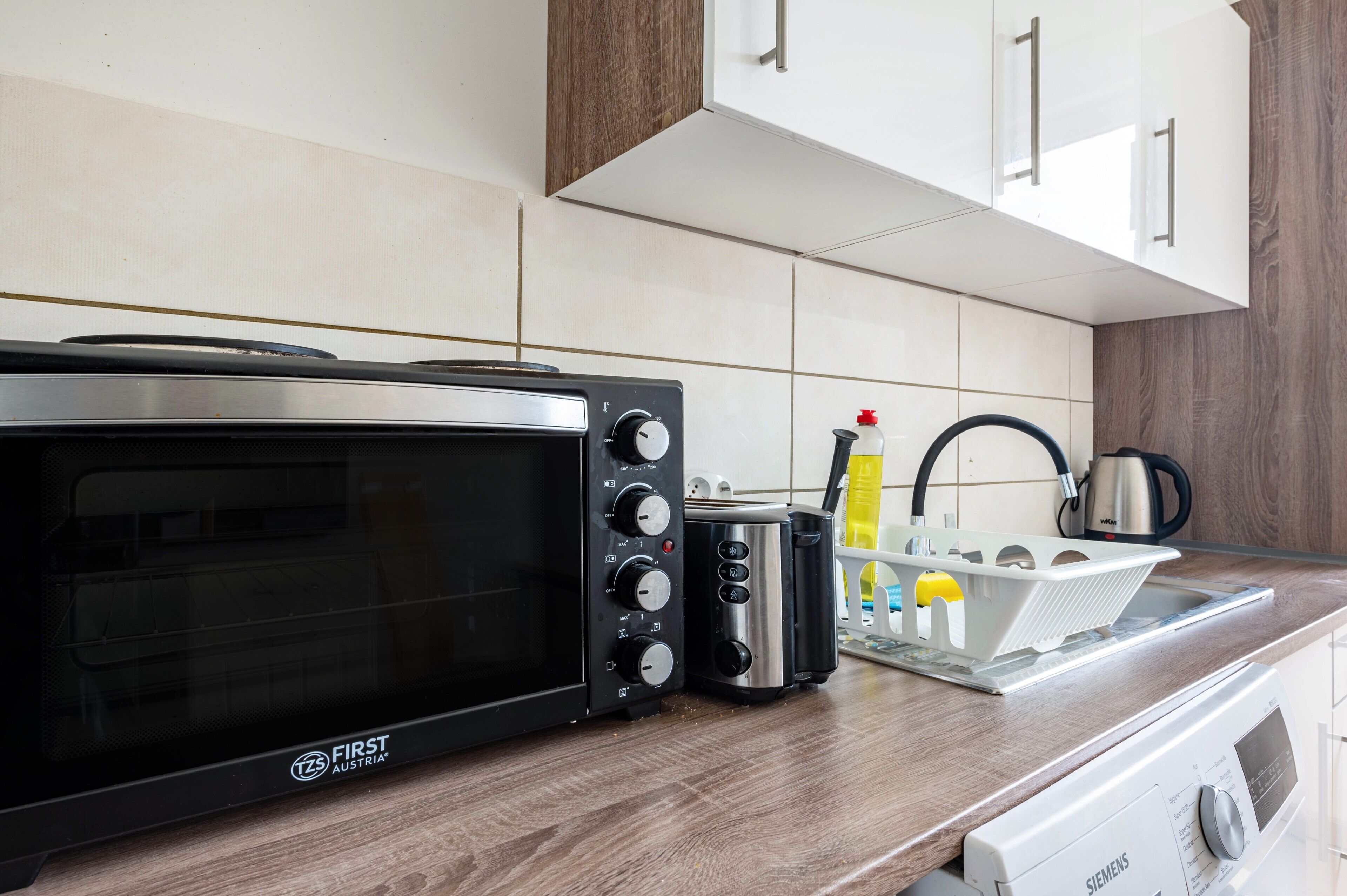 Een keuken met een zwarte magnetron, een broodrooster en een Siemens vaatwasser.