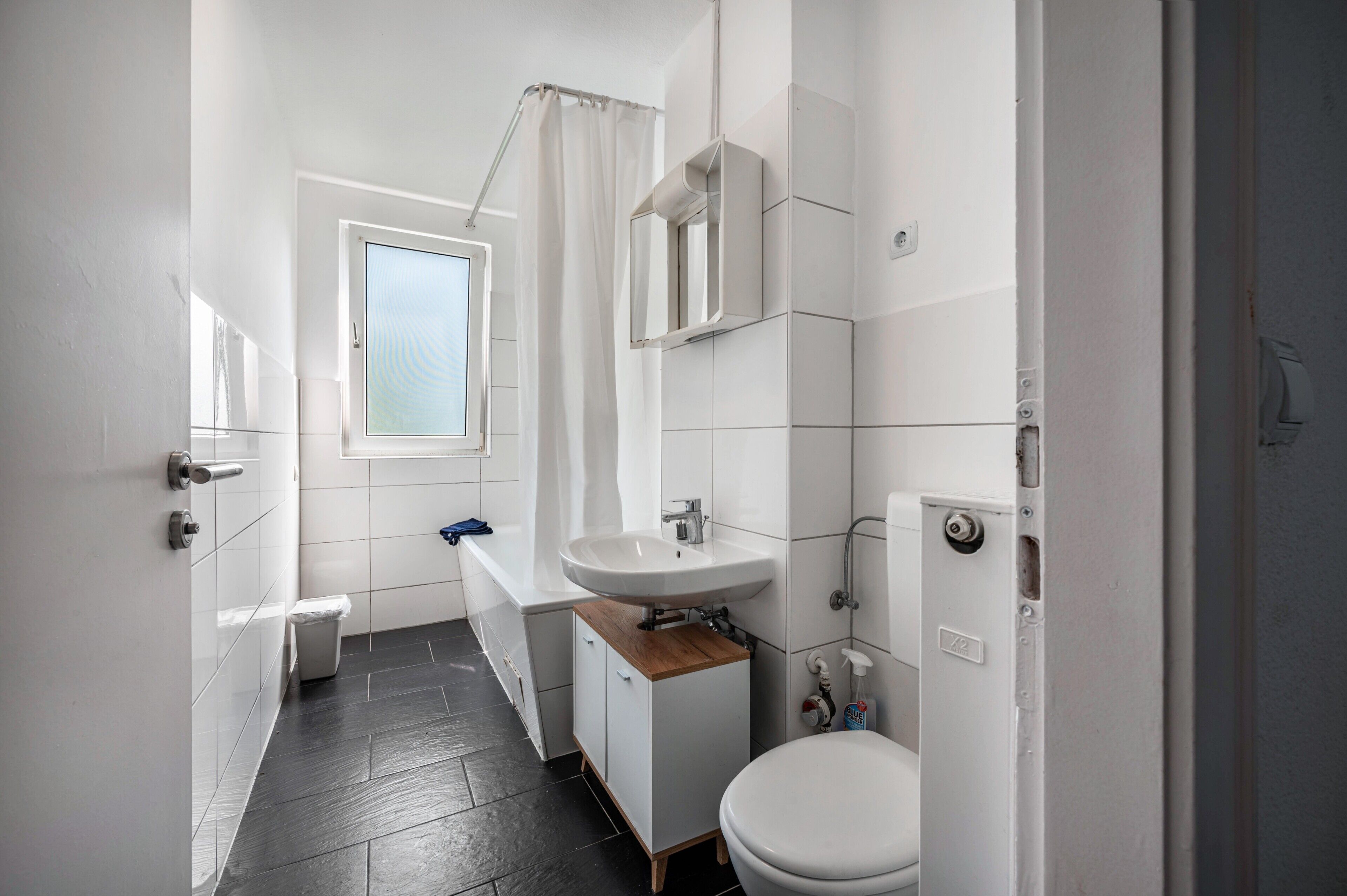 A compact bathroom with a white sink, toilet, and shower.