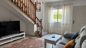 Un salon avec un escalier, un téléviseur, une table basse et un canapé.