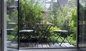 An outdoor patio with a table and chairs, surrounded by lush greenery. - Studio '1, 30qm' with Private Terrace, Wi-Fi and Air Conditioning (Freiburg)