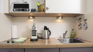 A kitchen with a microwave, kettle, and sink.