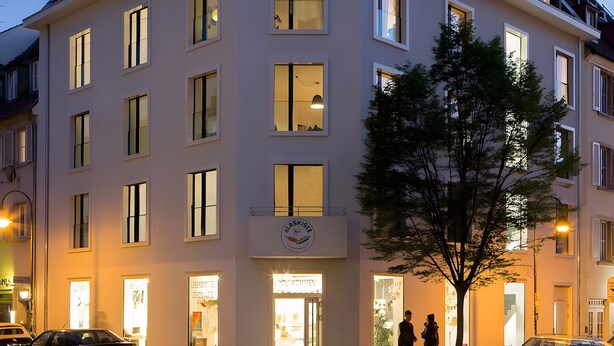 A multi-story building with a flat roof and large windows.