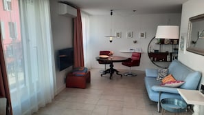 Un salon avec un canapé, une table à manger, un téléviseur et une lampe.