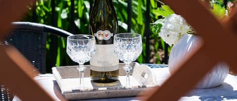 Una mesa dispuesta con una botella de vino Riesling Classic, dos copas y un arreglo decorativo de flores blancas.