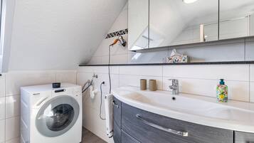 Ein modernes Badezimmer mit Waschmaschine, Waschbecken und Spiegel.