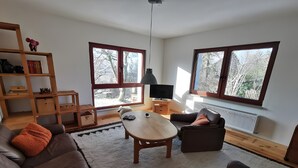 Una sala de estar con un sofá, una mesa de centro, un televisor y una estantería.