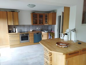 Une cuisine moderne avec des meubles en bois, un lave-vaisselle, une cuisinière et une machine à café.