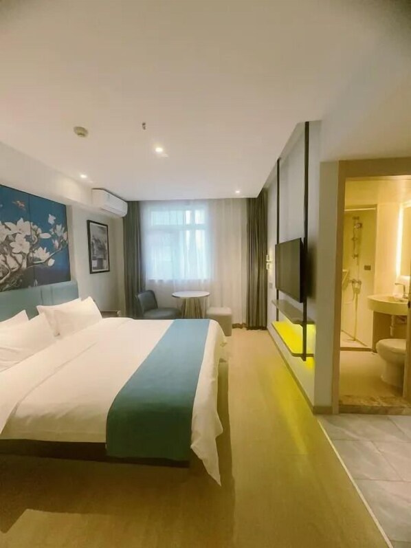 A hotel room with a large bed, a small table, a TV, and a bathroom visible through an open door. - YESTE Hotel (Shenzhen Nanshan Qianhai Daxin subway station) (Shenzhen)