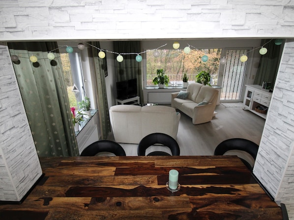Un salon moderne avec un canapé blanc, un téléviseur et une table à manger agrémentée d’une bougie.