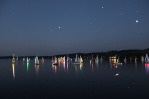 Un lago tranquilo de noche con veleros reflejados en el agua.