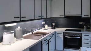 A modern kitchen with white cabinets, a built-in oven, a coffee maker, and a toaster.