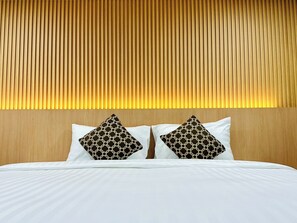 A hotel room with a wooden headboard, white bedding, and two patterned pillows. - The Cozy 77 - No Parking (Bangkok)