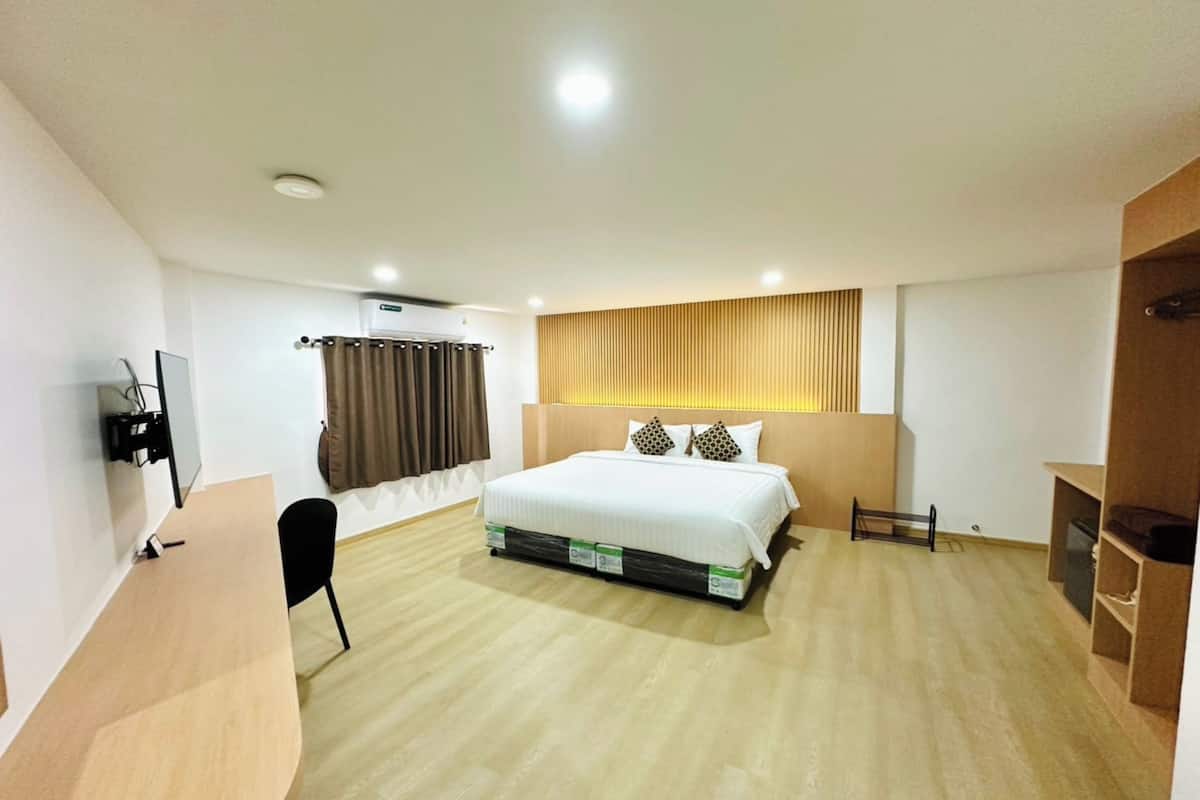 Hotellihuone, jossa on sänky, työpöytä, tuoli, televisio ja vaatekaappi.