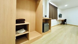 A modern room with a wooden wardrobe, a small desk with a chair, a television, and a refrigerator. - The Cozy 77 - No Parking (Bangkok)