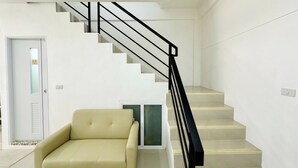A modern interior with a staircase, a beige sofa, and a door with a window. - The Cozy 77 - No Parking (Bangkok)