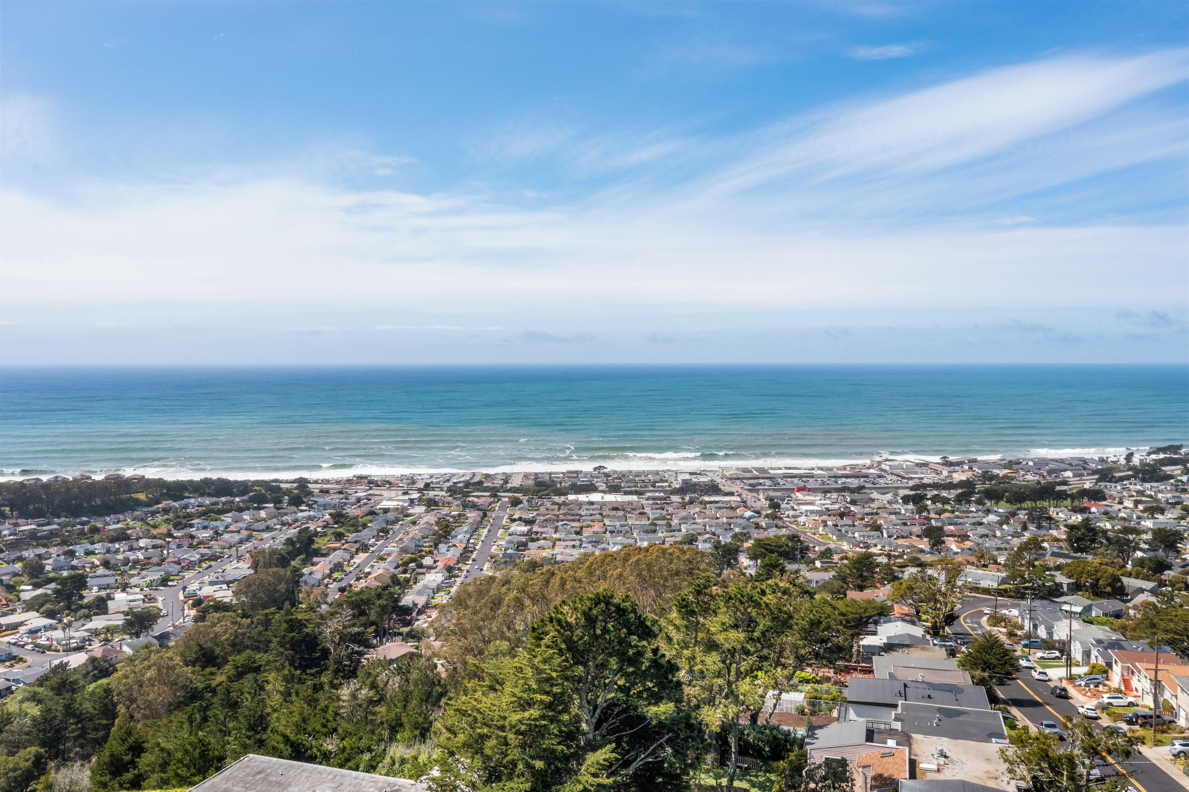 A coastal town with residential buildings, a beach, and a clear sky.