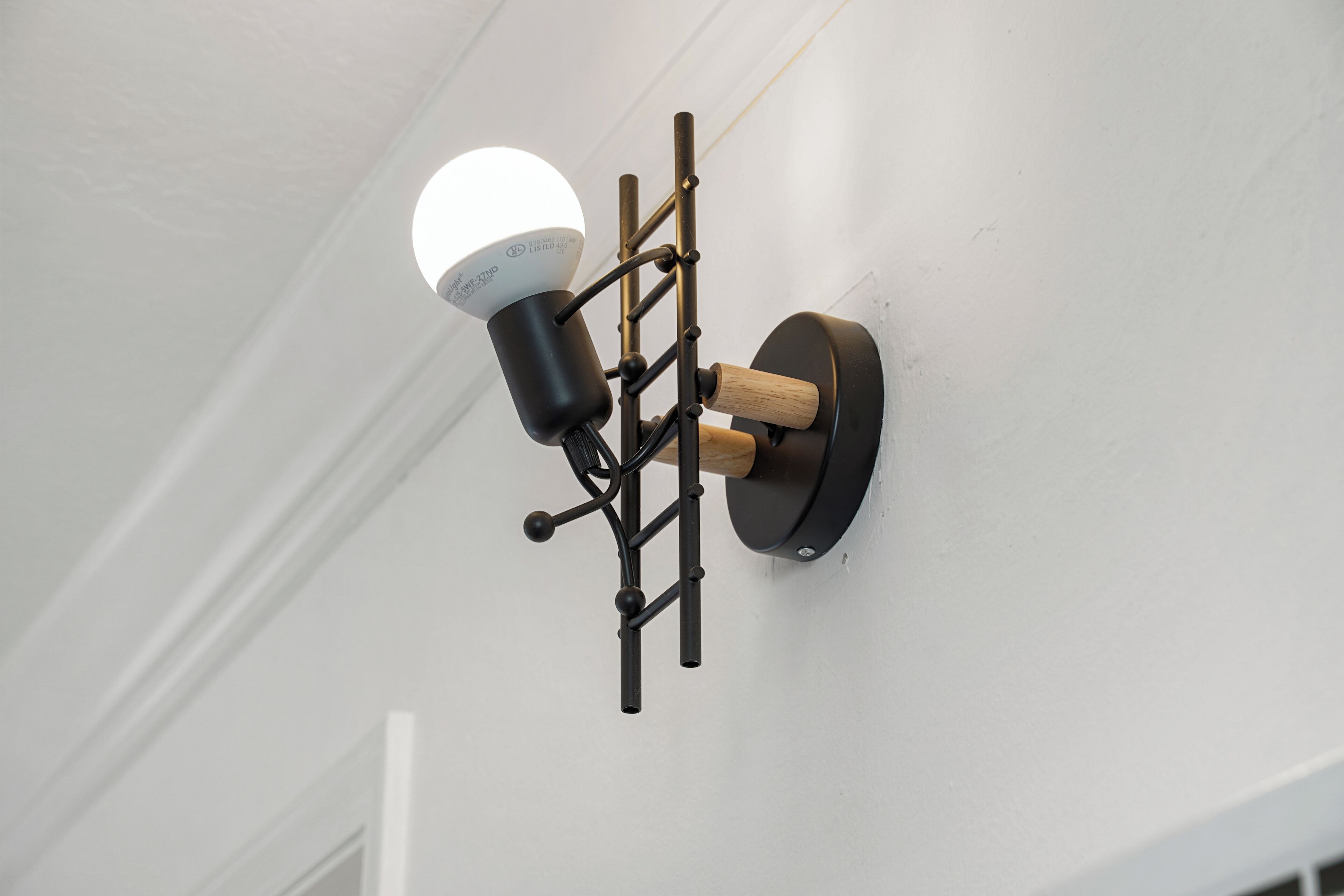 A wall-mounted light fixture with a spherical bulb and a black metal frame.