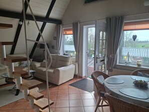 A cozy room with a staircase, a sofa, a dining table with chairs, and a view of the outdoors. - Apartment 'Ferienwohnung Rieck' with Private Terrace, Private Garden and Wi-Fi (Witzwort)