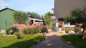 A residential property with a paved driveway, a brick wall, and a green building.
