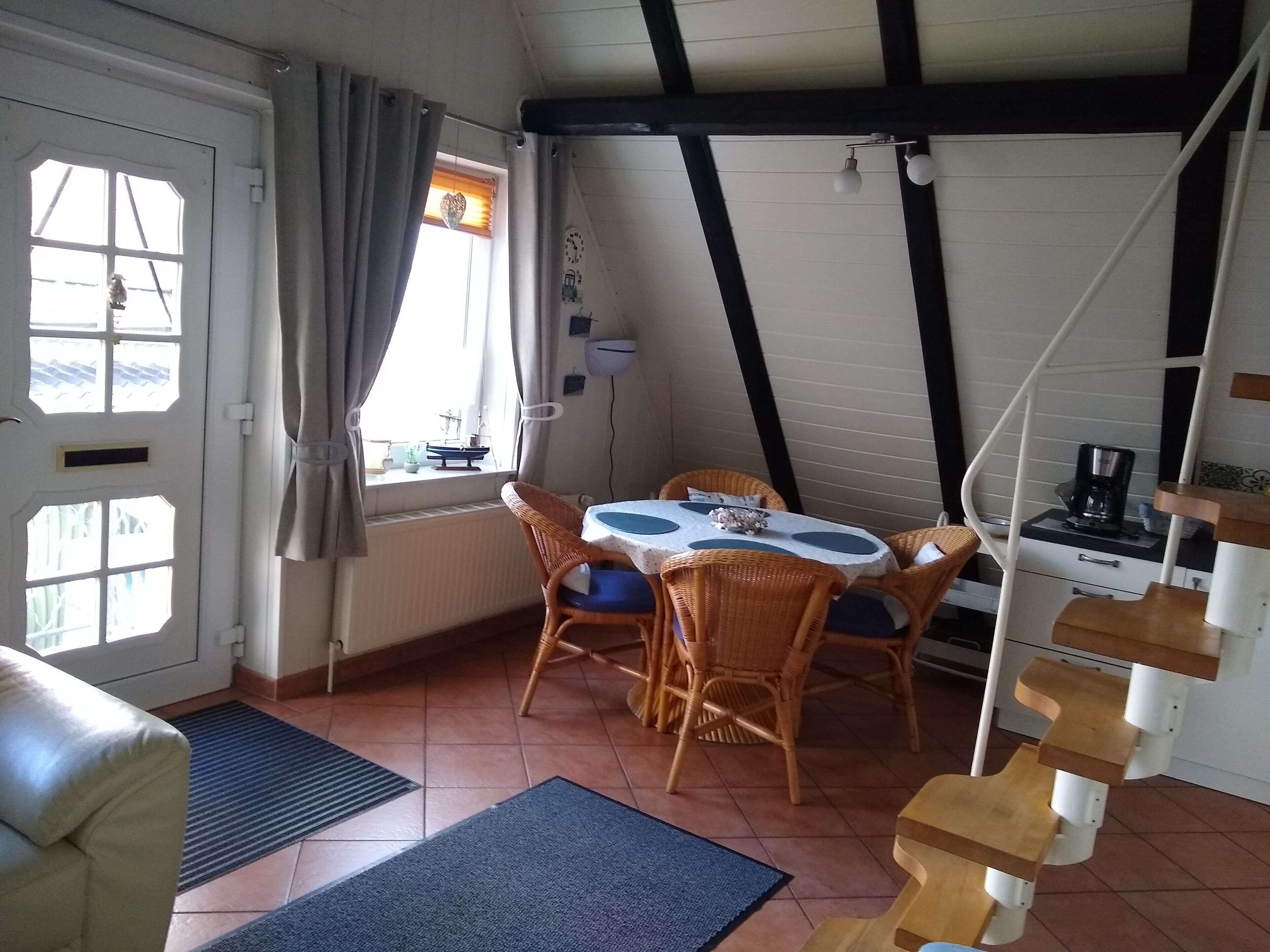 A dining area with wicker chairs, a table, and a coffee machine.
