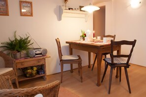 Een eethoek met een houten tafel, stoelen, een radio en een potplant.