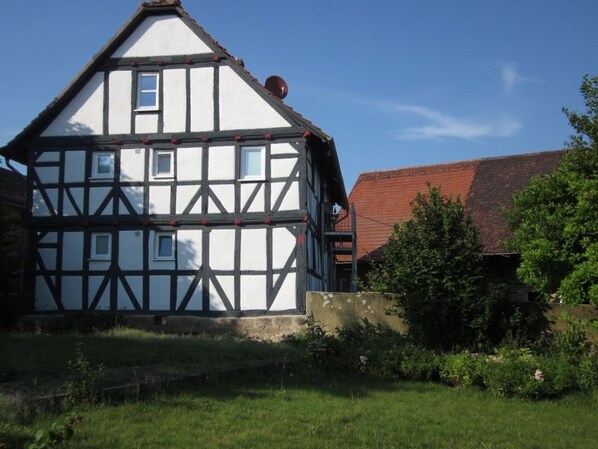 Ein traditionelles Fachwerkhäuschen mit geneigtem Dach, einem kleinen Fenster und einem Schornstein.