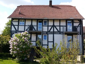 Een gebouw met twee verdiepingen, een pannendak, meerdere ramen en een balkon.
