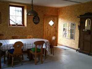 A dining area with a wooden table, chairs, and a hanging light fixture.