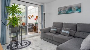 A modern living room with a grey sofa, a potted plant, and a large abstract painting on the wall.