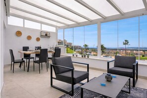 Una sala de estar moderna con comedor, ventanas grandes y vistas a la ciudad.