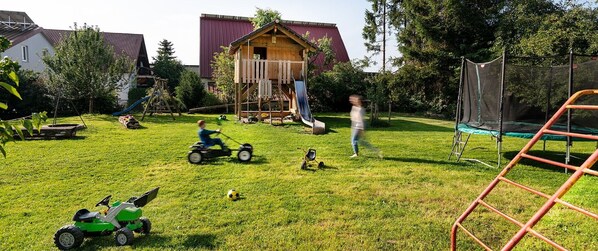 A backyard with a play area, including a slide and a swing set.