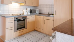 Eine Küche mit Holzausstattung, Backofen, Mikrowelle und Kaffeemaschine.