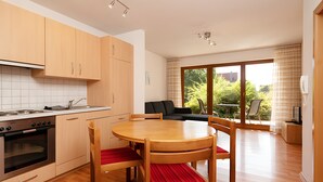 Une cuisine moderne avec des meubles en bois, une table à manger avec des chaises et un coin salon avec un canapé et un téléviseur.