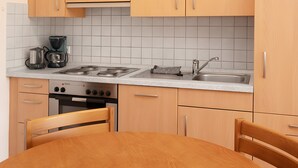Une cuisine avec des meubles de rangement en bois, une cuisinière à gaz, une machine à café et un évier.