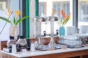A hotel reception area with a coffee station, tea station, and a display of glassware.