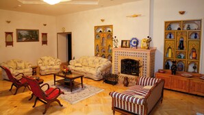 A traditional living room with a fireplace, two sofas, a coffee table, and a red armchair. - Ikat Villa (Tashkent)