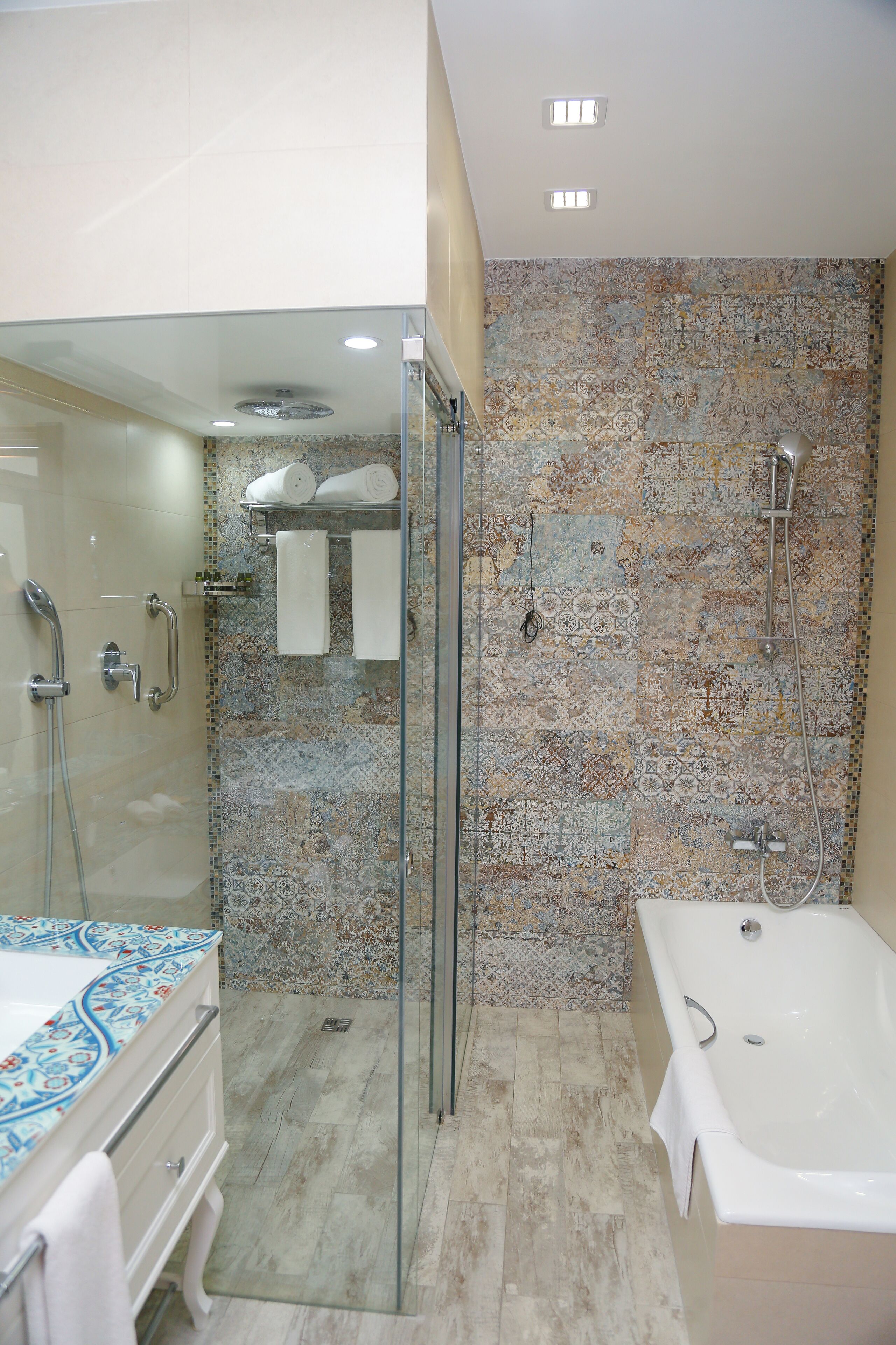 A modern bathroom with a glass-enclosed shower, a bathtub, and a tiled wall.