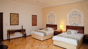 A hotel room with two beds, a desk, and a chair. - Ikat Villa (Tashkent)
