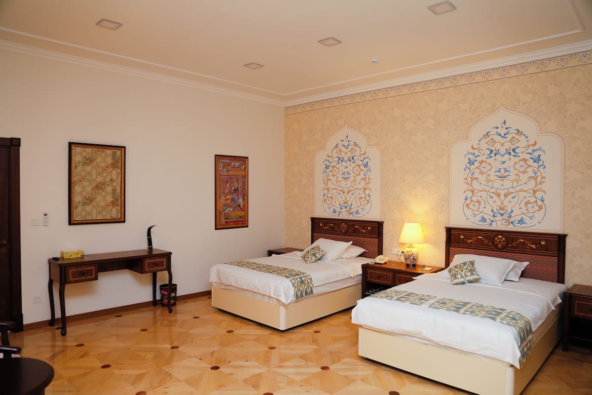 A hotel room with two beds, a desk, and a chair.