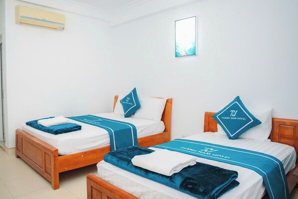 A hotel room with two beds, each with a blue bedspread and matching pillows. - Thanh Nam Hotel Quan Lan By Bay Luxury (Van Don)