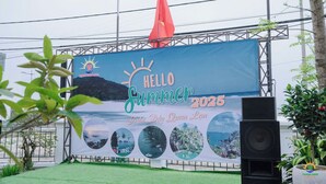 Eine Bühne mit einer Bannermarke, die "HELLO Summer 2025" und "Binh Diu Quan Lan" zeigt, und Bildern von Küstenlandschaften.