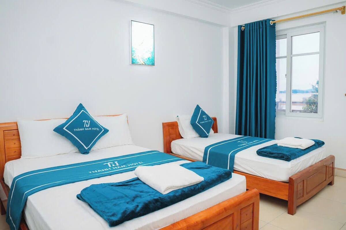 Een hotelkamer met twee bedden, elk voorzien van passende kussens en een blauw sprei.