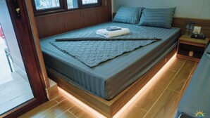 Ein modernes Hotelzimmer mit einem Bett, Holzboden und einem Nachttisch mit Lampe.