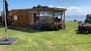 Un piccolo chalet in legno con veranda vetrata, area patio e vista mare.